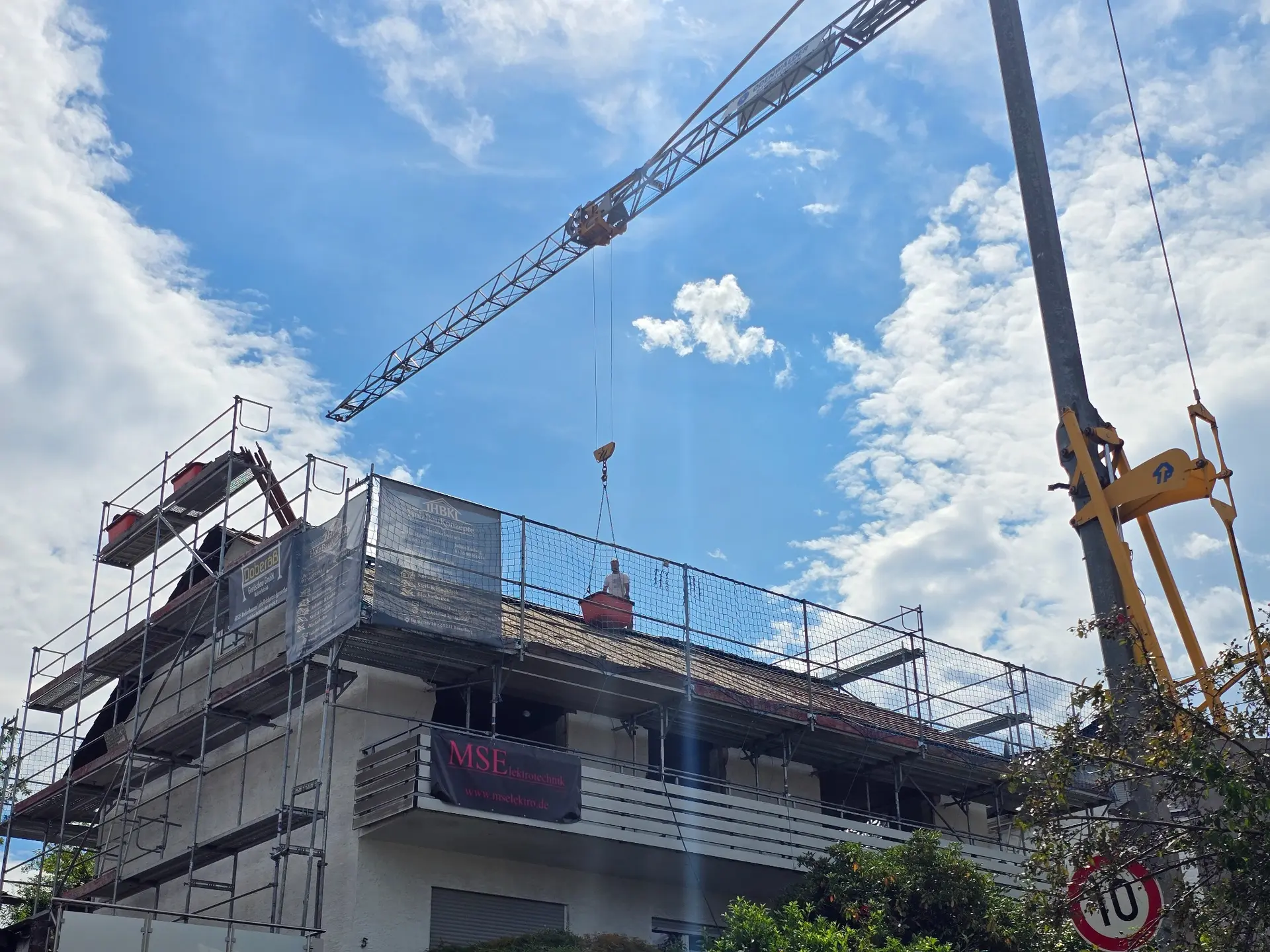 Eingerüstetes Gebäude mit aufgebautem Kran zu Beginn der Dacharbeiten