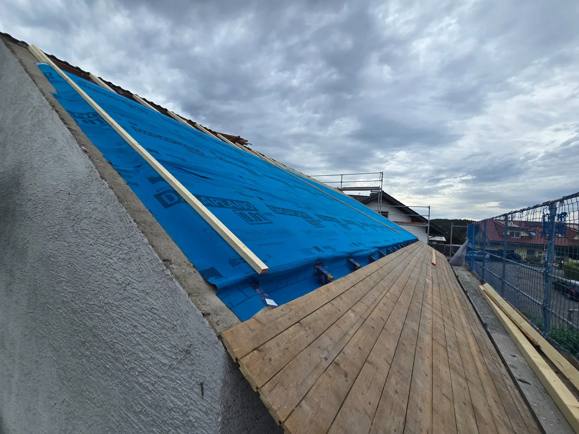 Dachfläche mit blauer Vordeckung und beginnender Unterkonstruktion